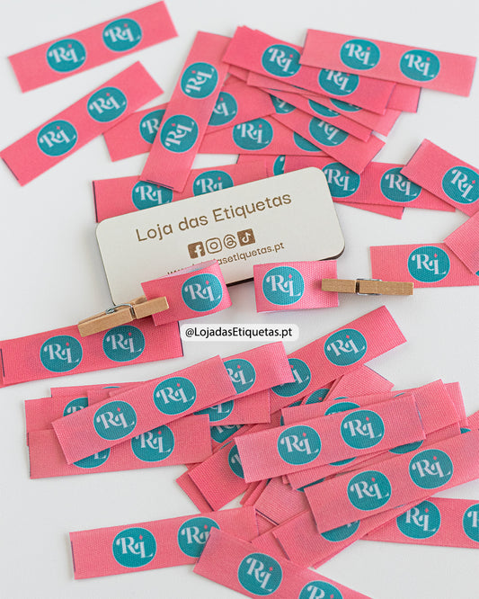 Etiquetas dobráveis personalizadas em tecido com impressão de alta definição na totalidade da etiqueta. Etiqueta rosa com logotipo em branco