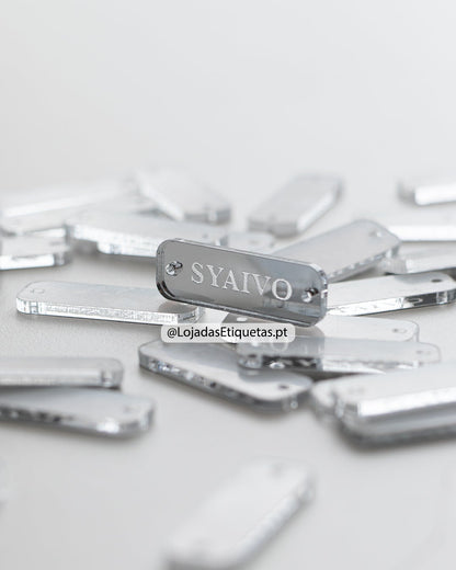 Etiqueta personalizada com logotipo em acrilico espelhado prateado com furos laterais.