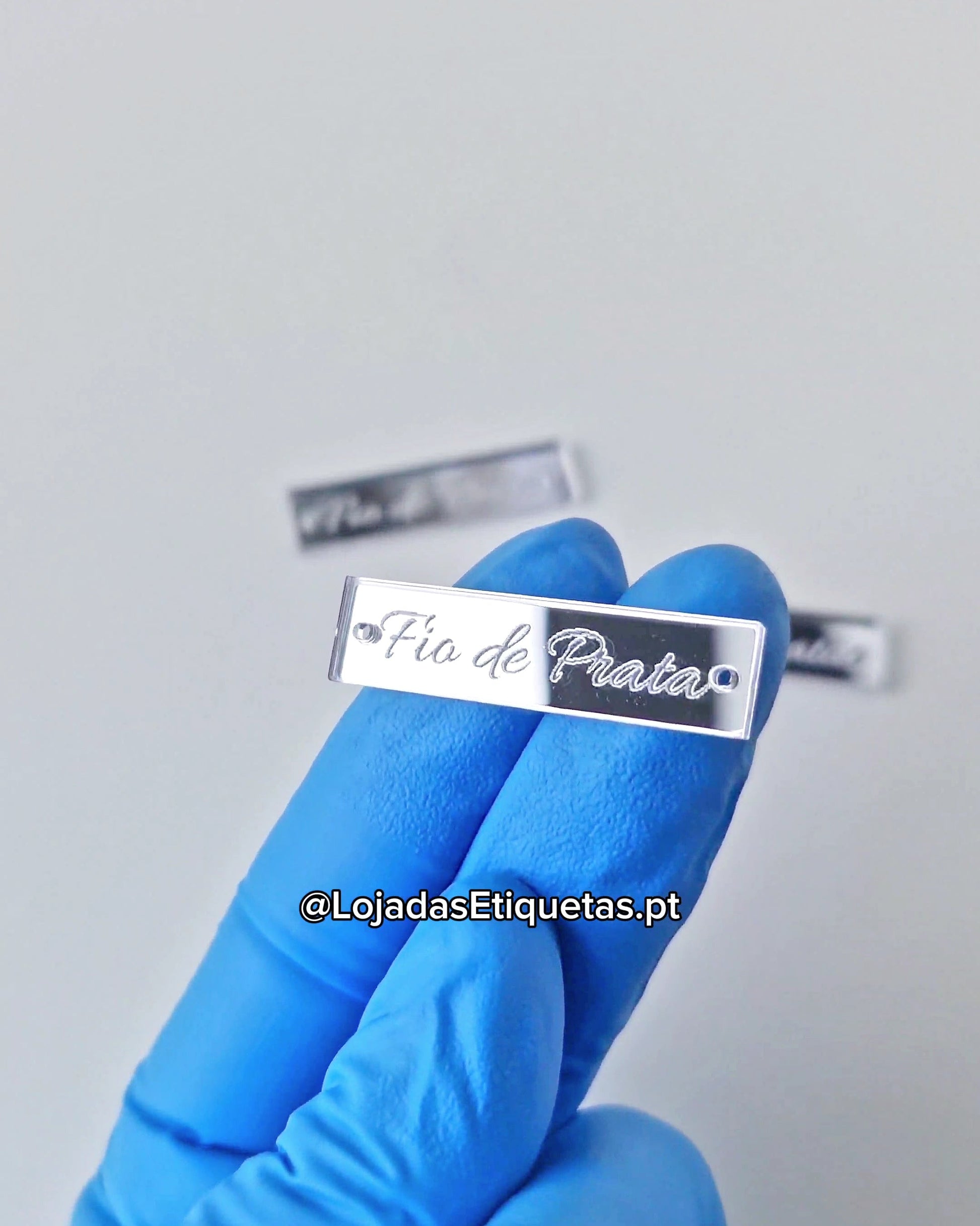 Etiqueta personalizada com logotipo em acrilico espelhado prateado com furos laterais.