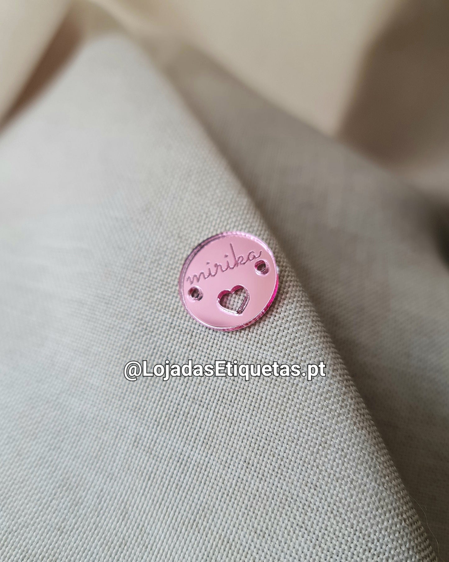 Etiqueta em acrilico rosa espelhado com logotipo gravado a laser e um coração por baixo. Em tom rosa.