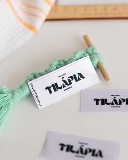 Etiquetas em cetim de dupla face para peças de fabrico artesanal, com impressão a preto do logotipo e handmade por baixo.